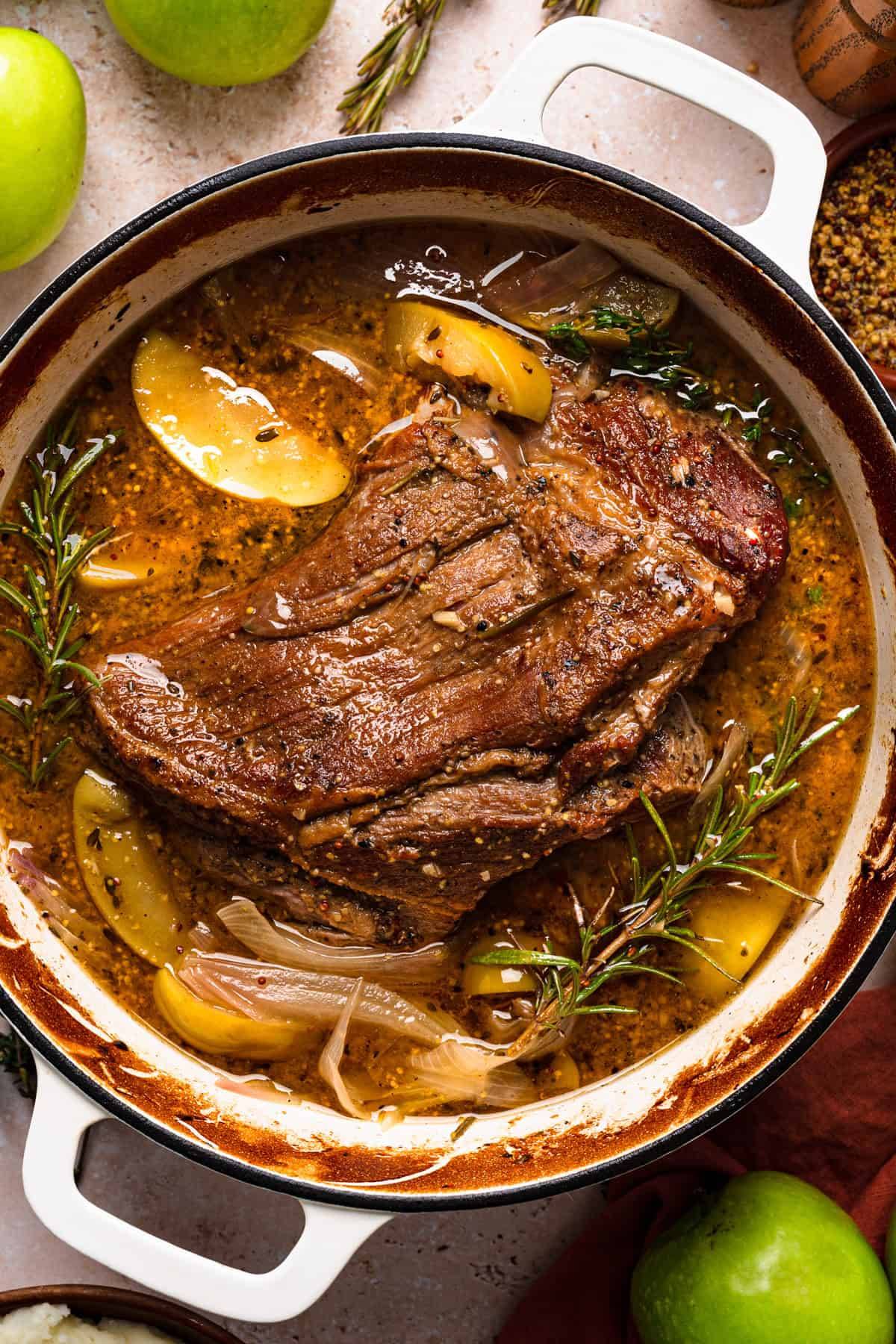 Apple Cider Braised Pork Shoulder in a white Dutch oven.