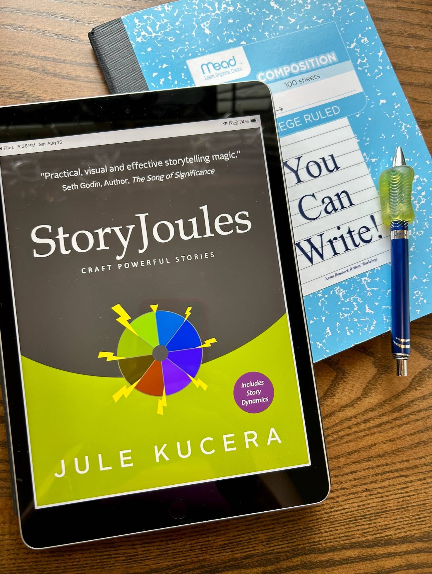 StoryJoules handbook on an iPad, with a composition notebook & pen
