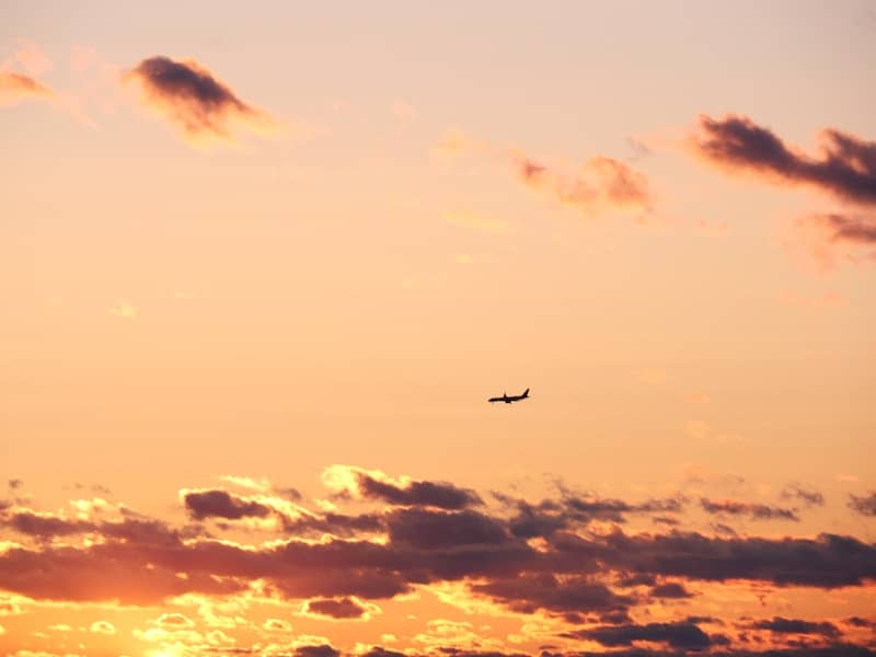 Airplane flying through clouds at sunset