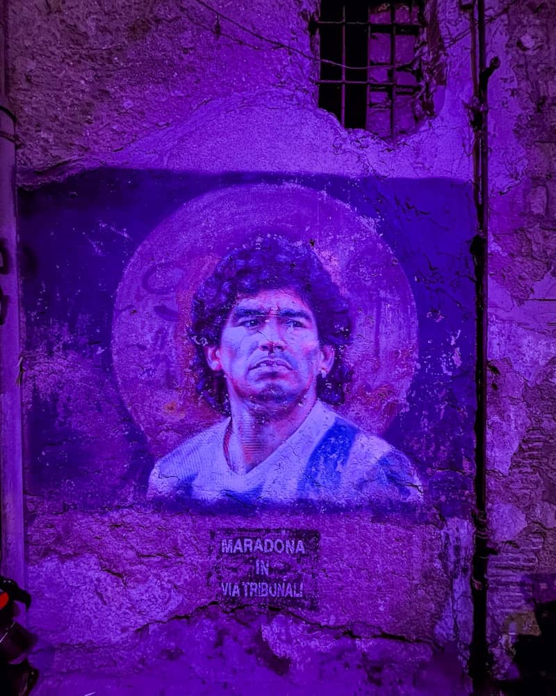 Mural of diego maradona illuminated by purple light.