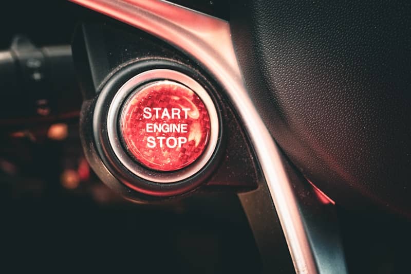 Red "start engine stop" button on a car dashboard.