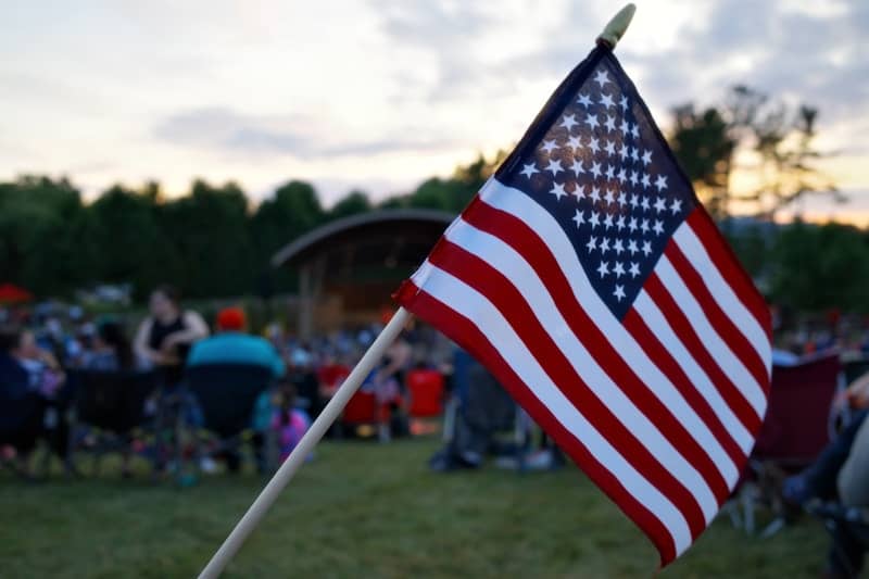 American flag waving at an outdoor gathering during sunset.