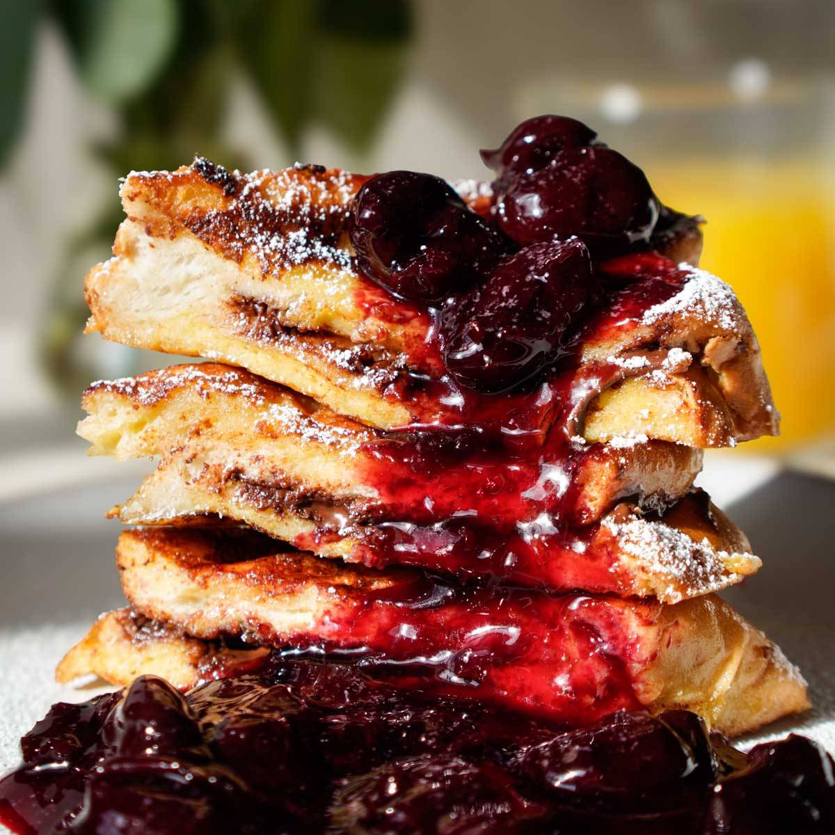 Layers of chocolate stuffed French toast with cherry compote on top