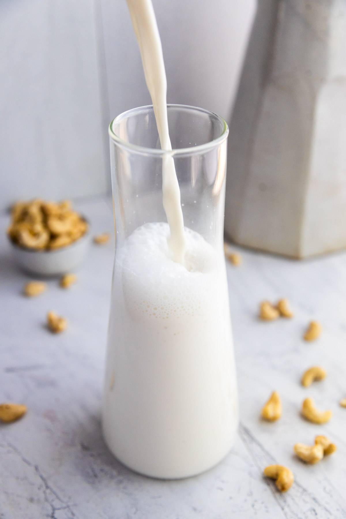 Homemade cashew milk pouring into a glass.