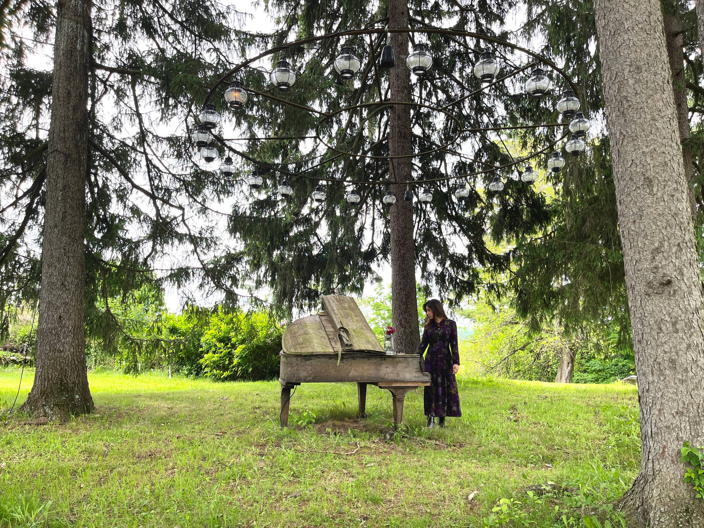 A mysterious woman plays an abandoned piano in the woods