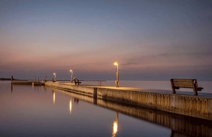 Lamps on a pier reflecting off calm water