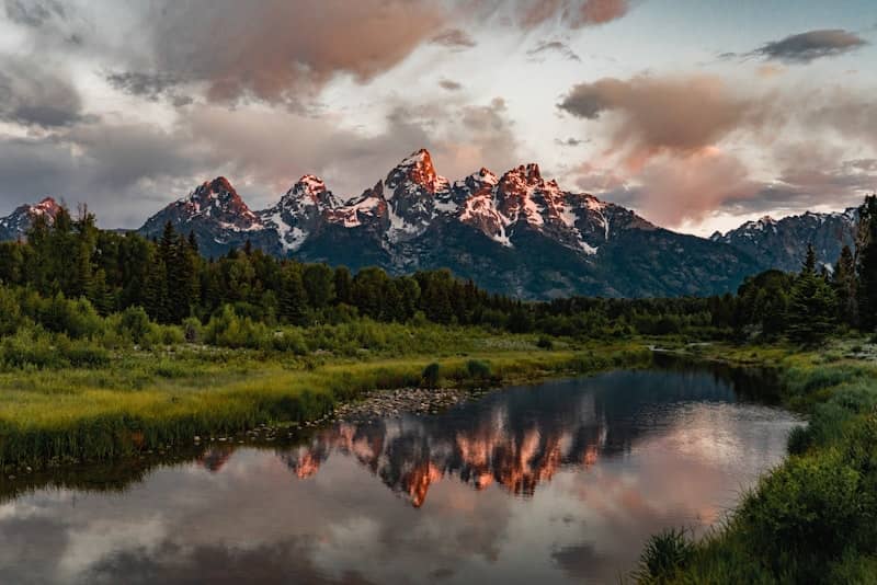 the mountains are reflected in the still water of the river