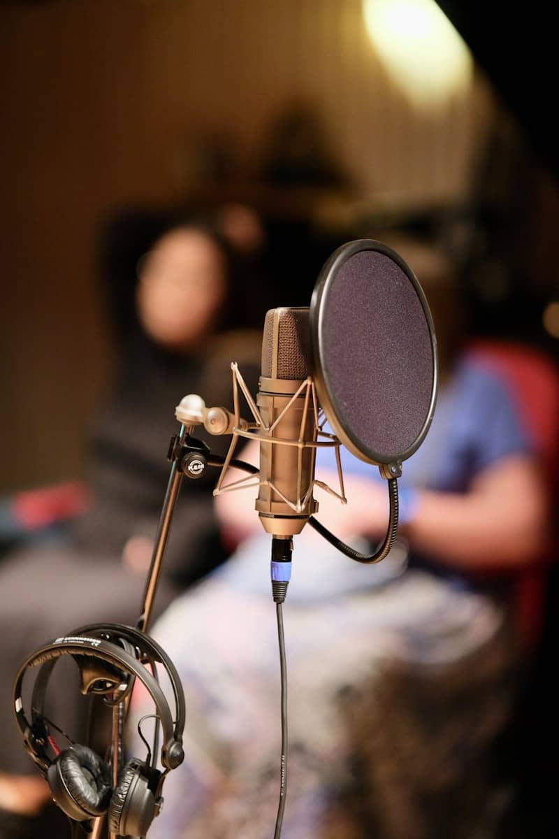 A professional studio microphone with pop filter and headphones.