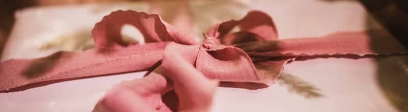 A hand tying a ribbon on a gift box