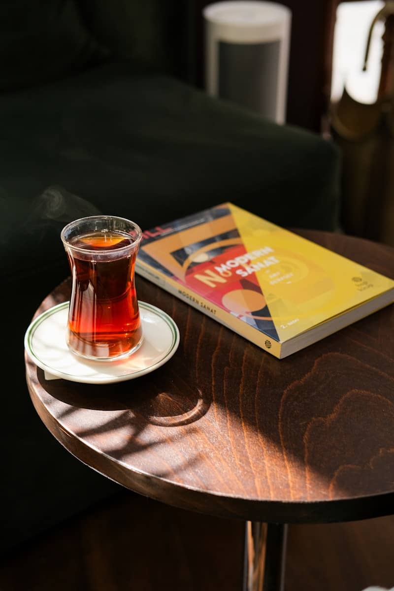 Tea and a book rest on a wooden table.