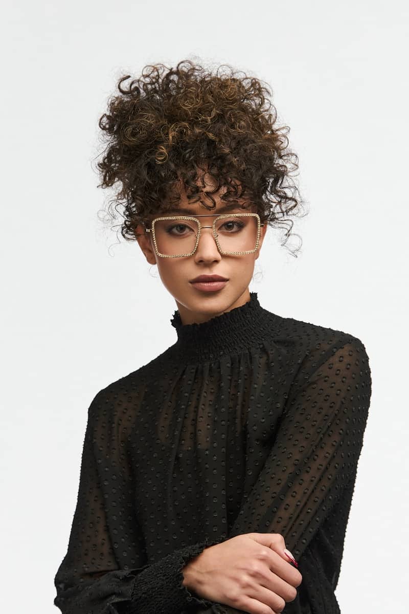 Stylish woman with curly hair wearing glasses.