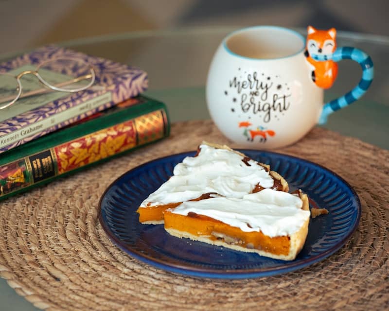 A piece of pie on a plate next to a cup of coffee