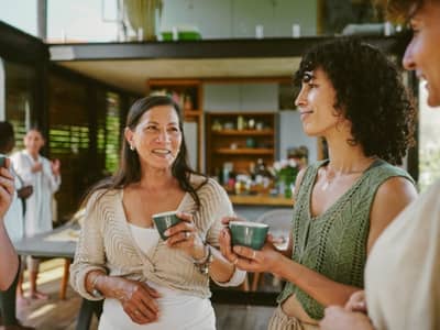 Woman in midlife smiling and talking with a new friend, showing how to make friends as an adult