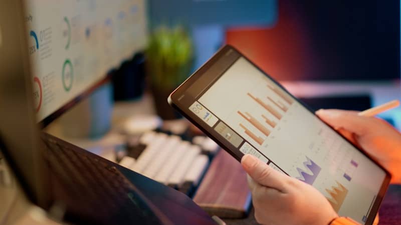 Someone analyzes financial data on a tablet.