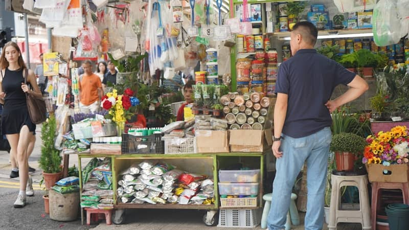 People walk past a busy outdoor market stall.