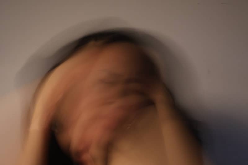 Person covering face with hands, blurred motion.