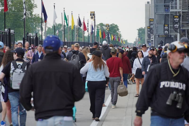 People walk down a crowded street with flags.