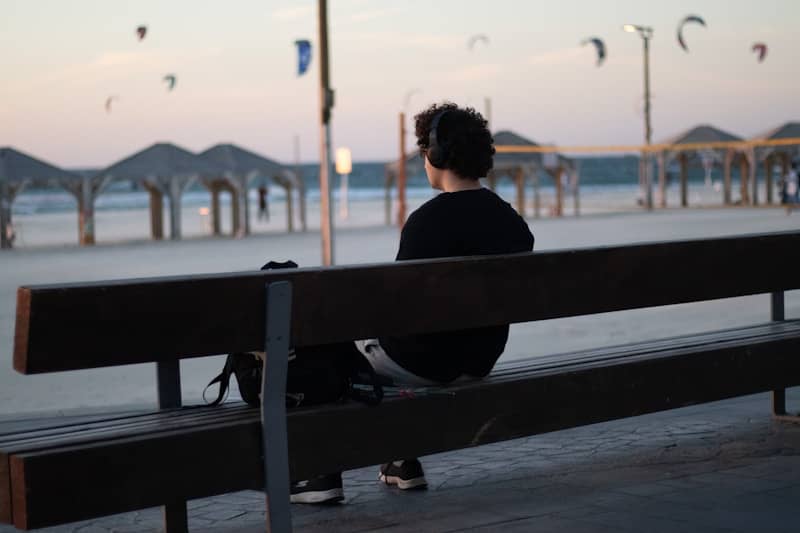 A person sitting on a bench in front of a body of water