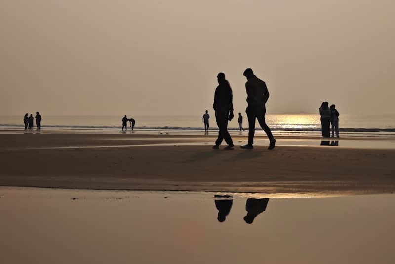 Silhouettes of people walking on a beach at sunset