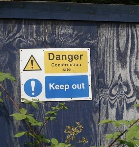 Blue wooden fence with danger and keep out construction signs.
