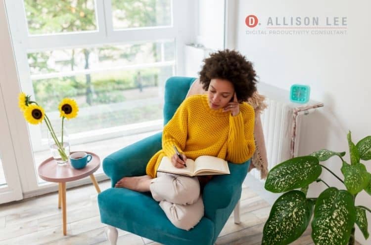woman sitting in a chair writing in her journal