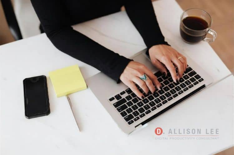 Person working at laptop with coffee and sticky note nearby
