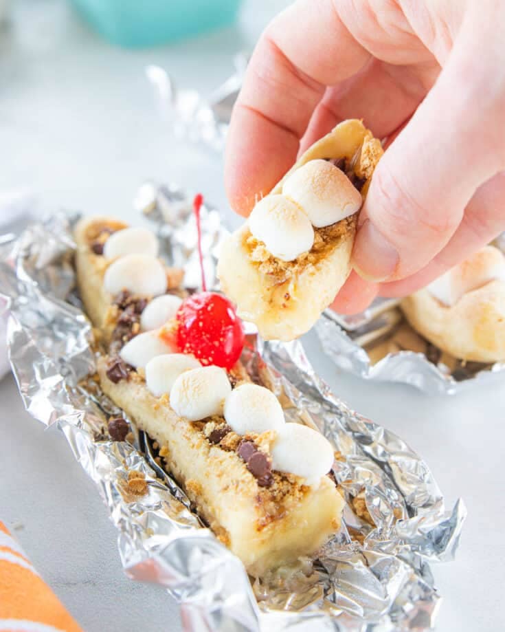 hand holding bite of a banana topped with marshmallows