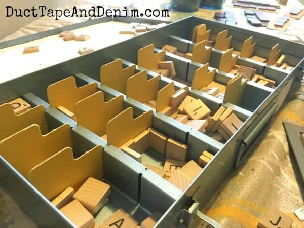 A vintage metal slide organizer used to sort Scrabble tiles.