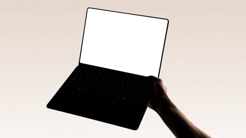 A hand is holding a laptop.