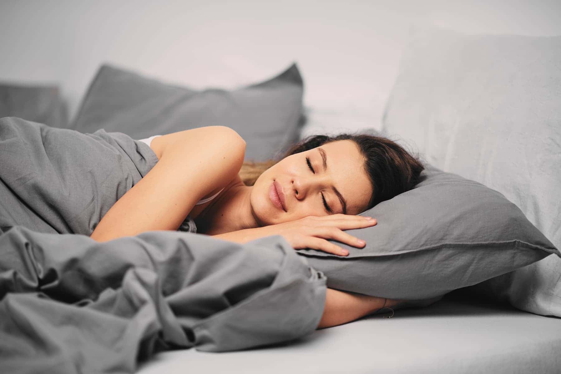 A content woman wakes up in her bedroom after a good night's sleep, understanding the true meaning of beauty sleep.