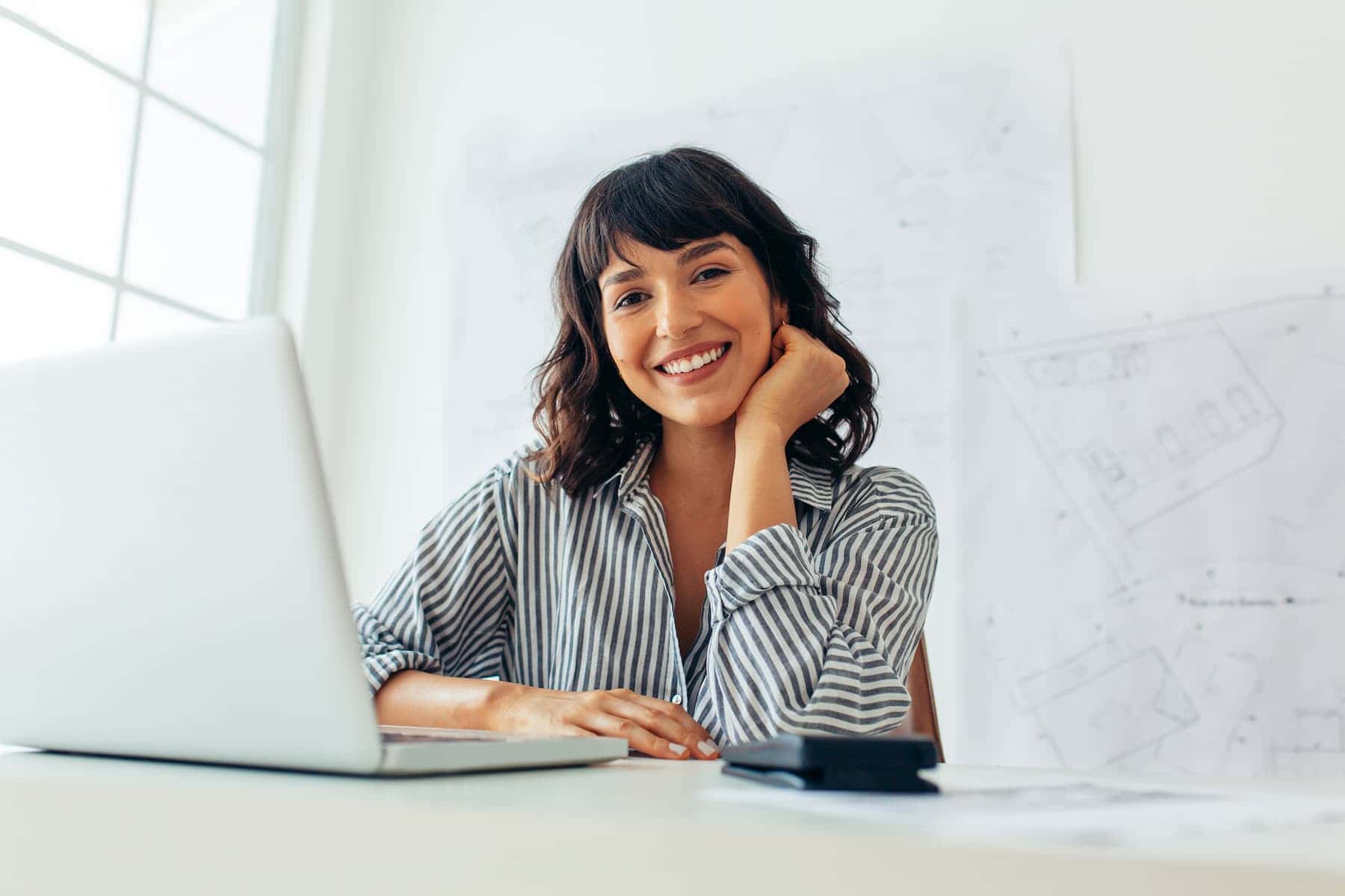 A smiling woman working at her desk shows how confidence and positivity are simple attractive tips that elevate everyday presence.