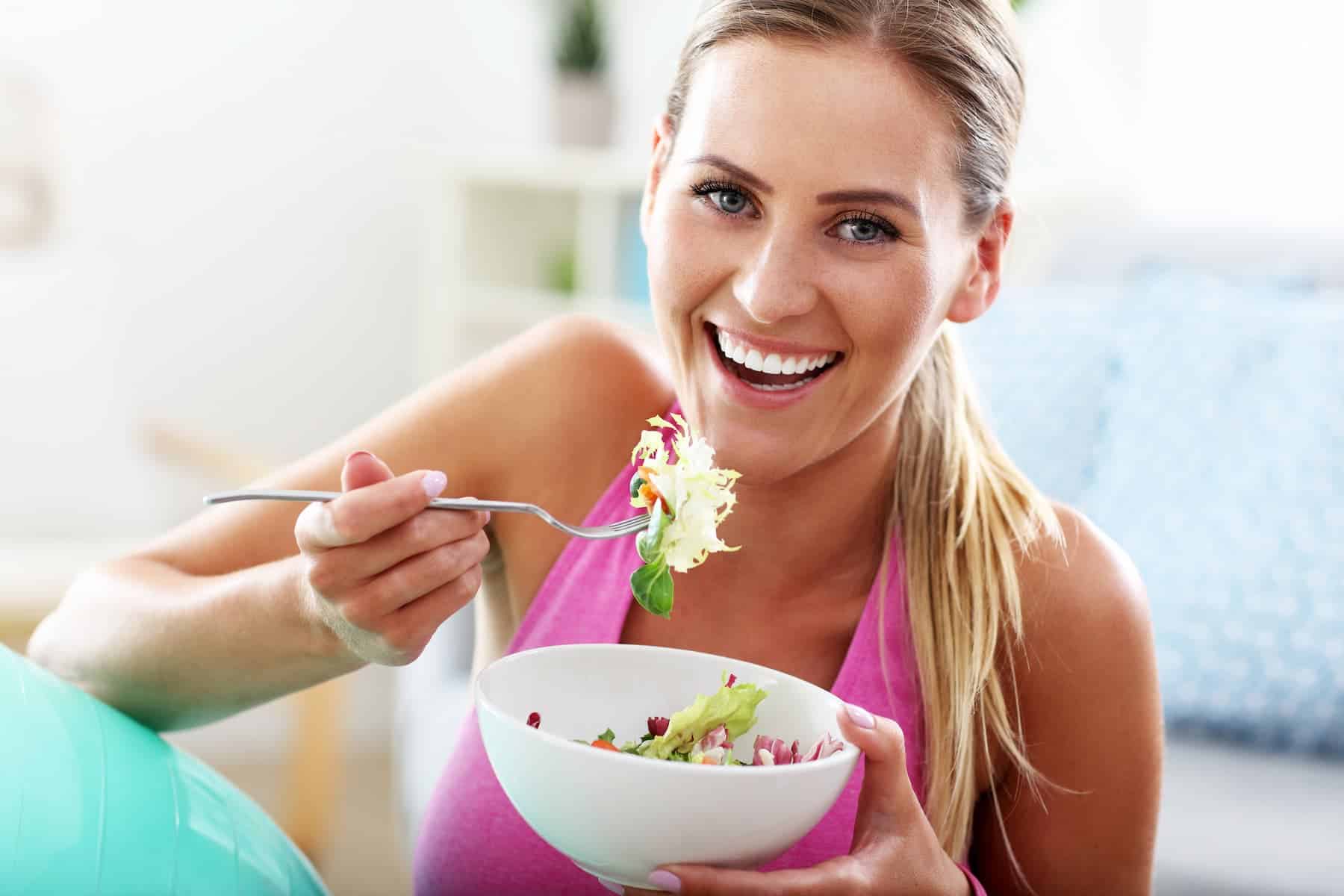 A woman enjoys a fresh salad, highlighting best foods for skin that support a healthy, radiant glow.
