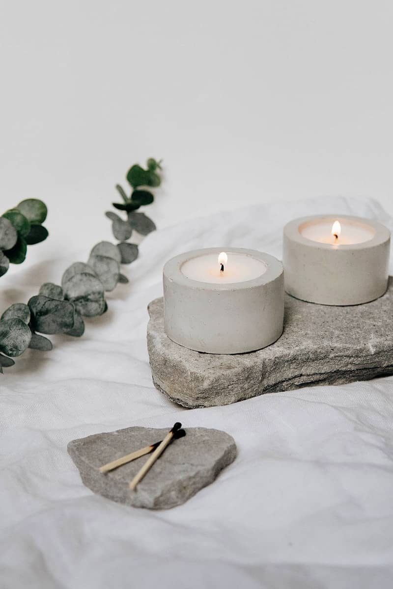 white pillar candle on gray rock