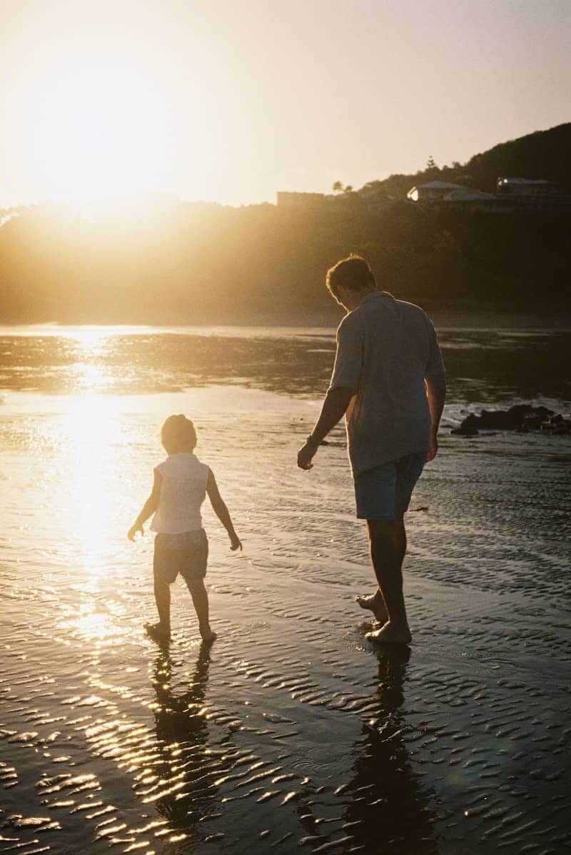 Father and child walk together at sunset.