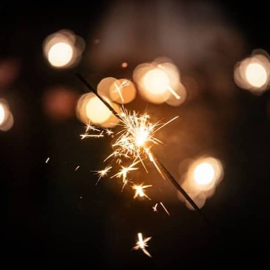 A sparkler burning brightly with bokeh lights