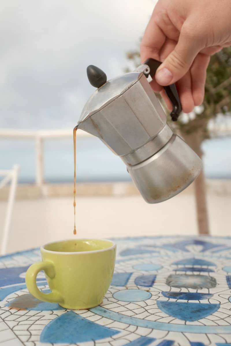 A person pouring coffee into a cup on a table