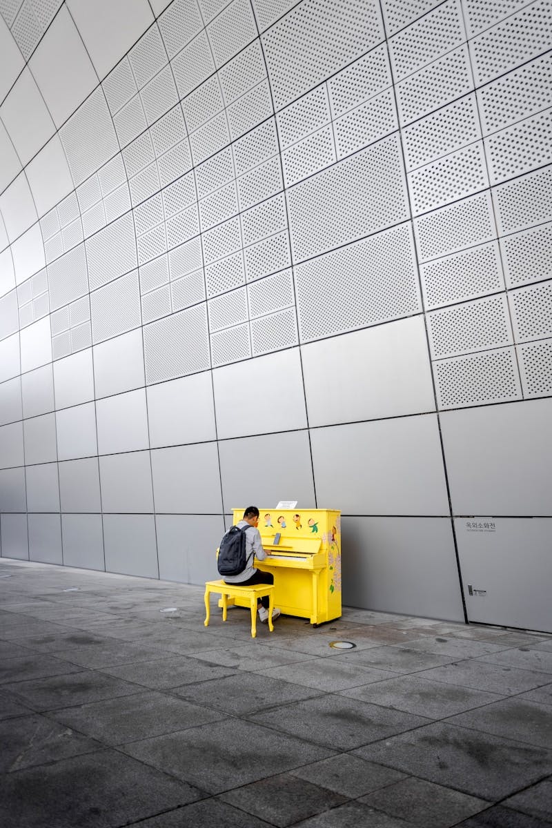 man in yellow jacket sitting on yellow plastic chair