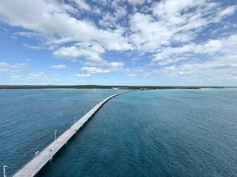 A long pier going to a small island under a beautiful blue sky.
