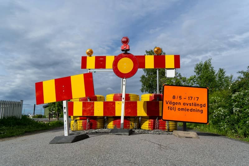 A road barrier with red and yellow stripes and a sign in Swedish