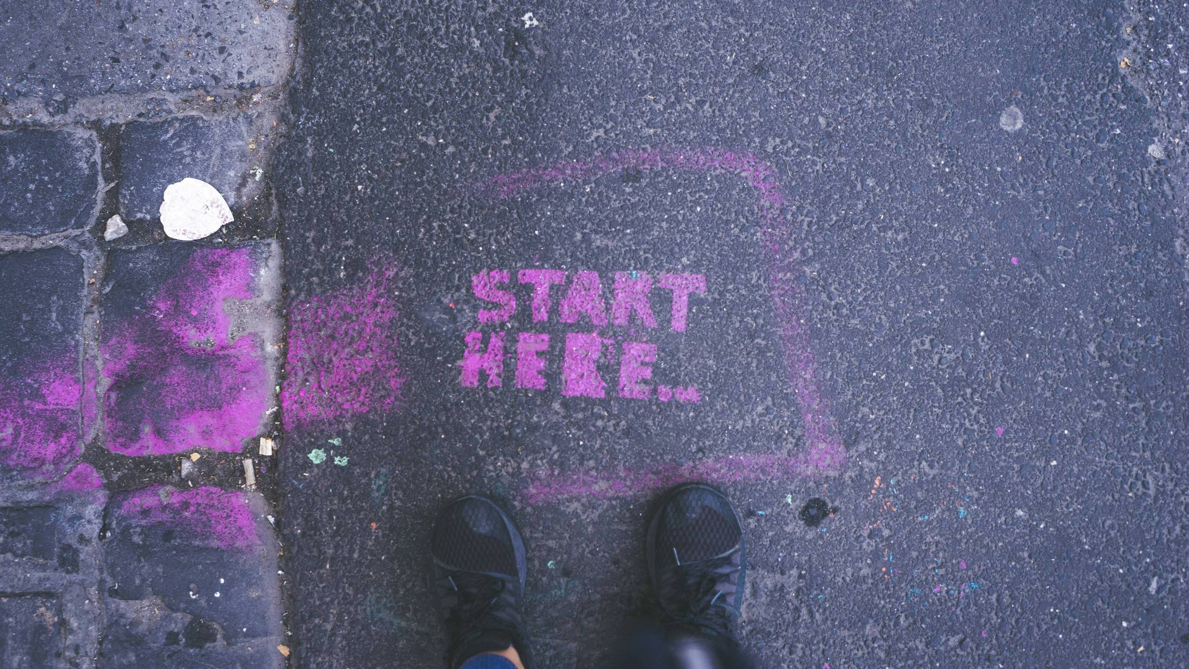 Start Here written in purple chalk on the street