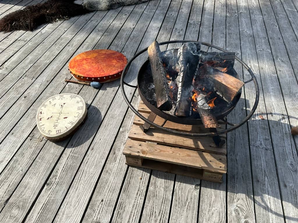 A small campfire in an ironcast wide pan with two shamanic drums next to it