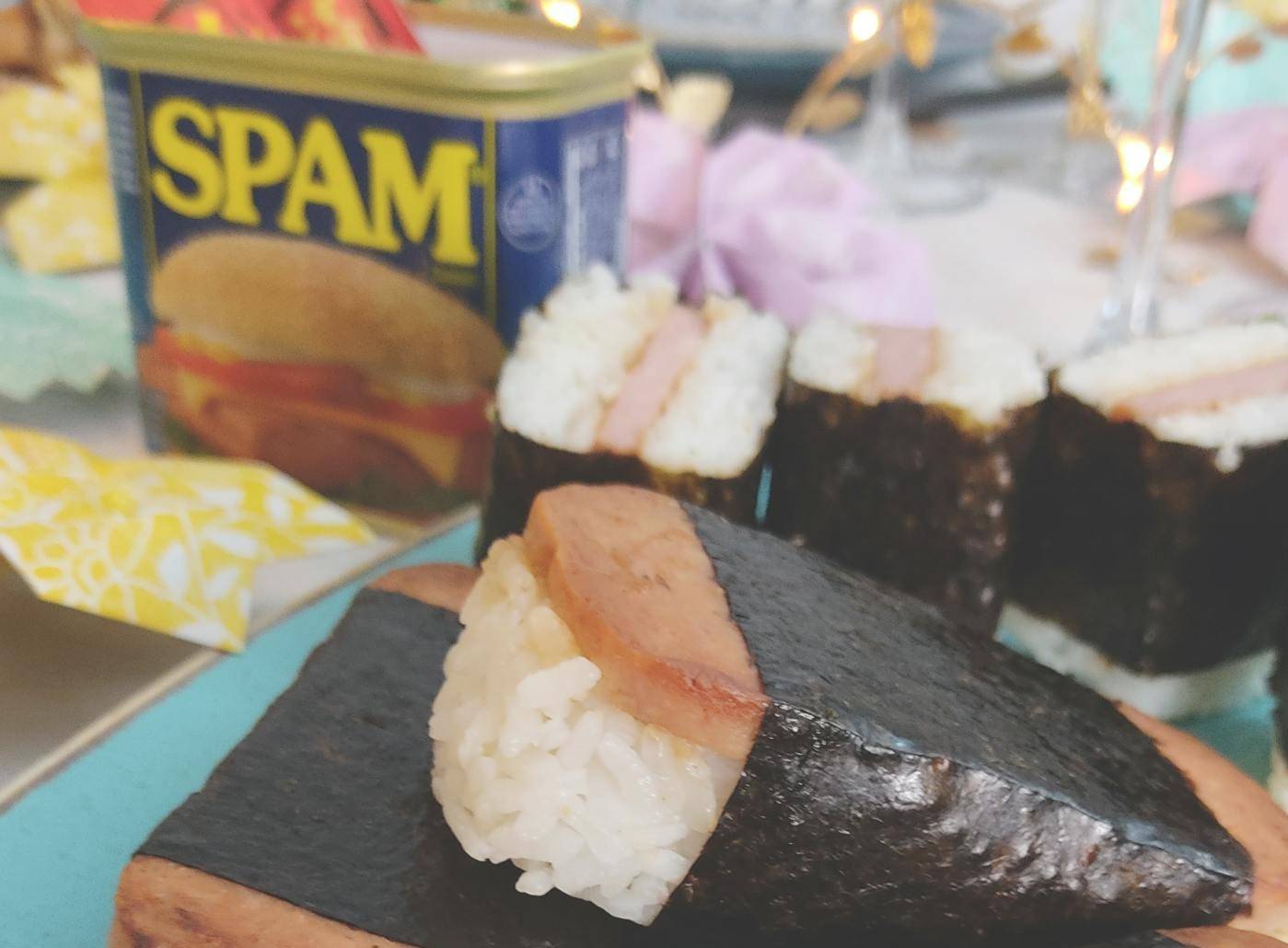 August 8 is National Spam Musubi day, this image is a plate of spam musubi with a spam can and three halves of musubis in the back