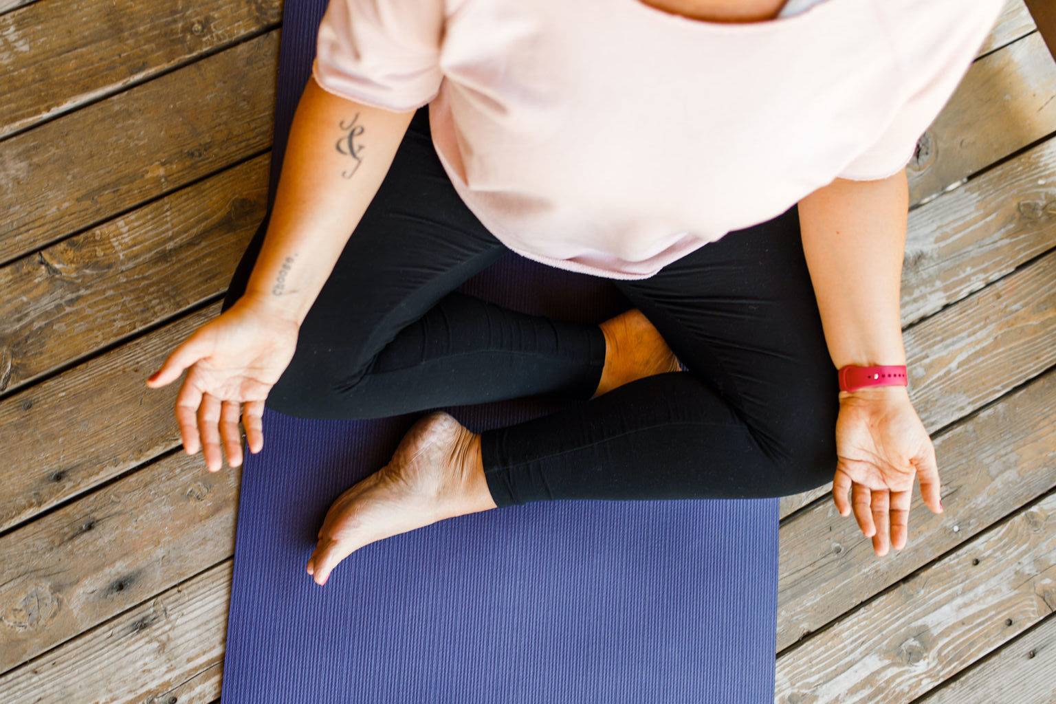 A woman sitting cross-legged, hands resting on her knees with palms facing up.