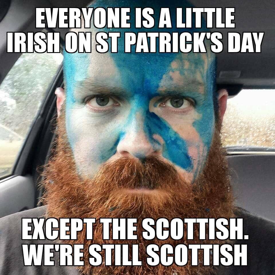 Meme featuring a man with a ginger beard sitting in a car, his face painted in blue and white in the style of the Scottish Saltire flag. Text reads: 'Everyone is a little Irish on St Patrick's Day except the Scottish. We're still Scottish.' The man's expression is stern and unimpressed, reinforcing the joke.