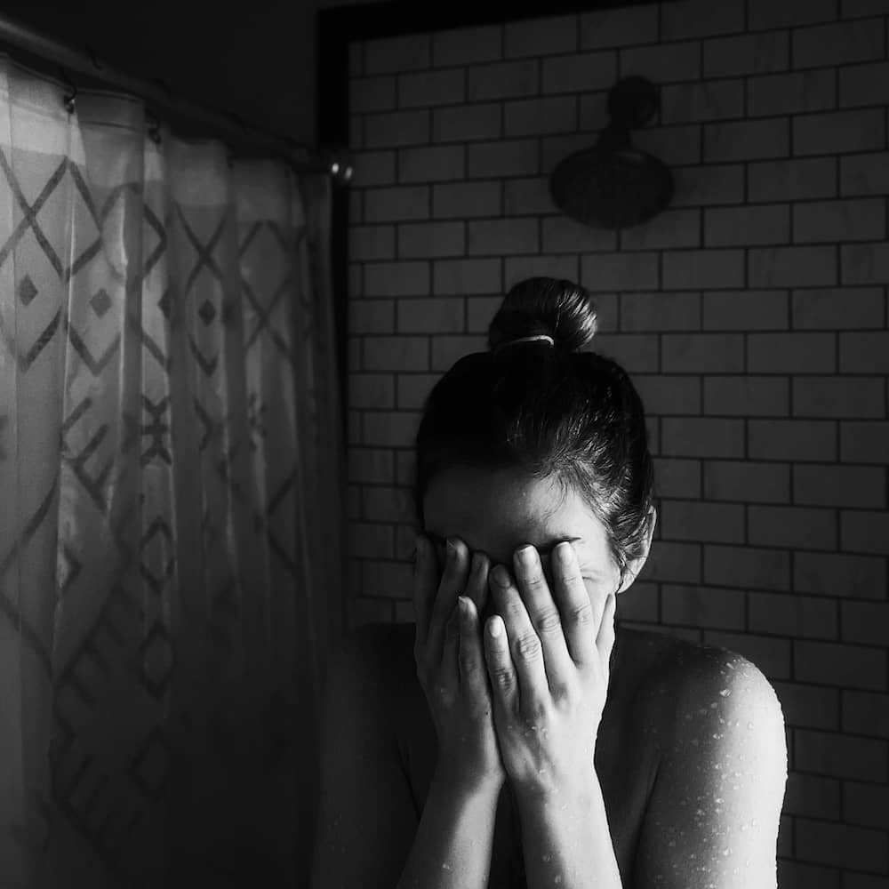 Woman covering her face in grief, black and white photo representing anger at God during grief after losing a parent