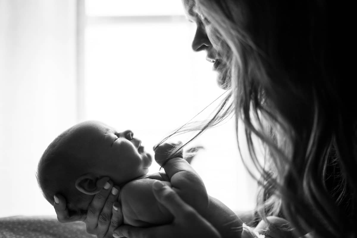 A parent holding a newborn baby close, representing the bittersweet joy of motherhood after loss