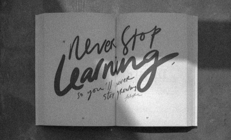 Open book with "never stop learning" written on pages.