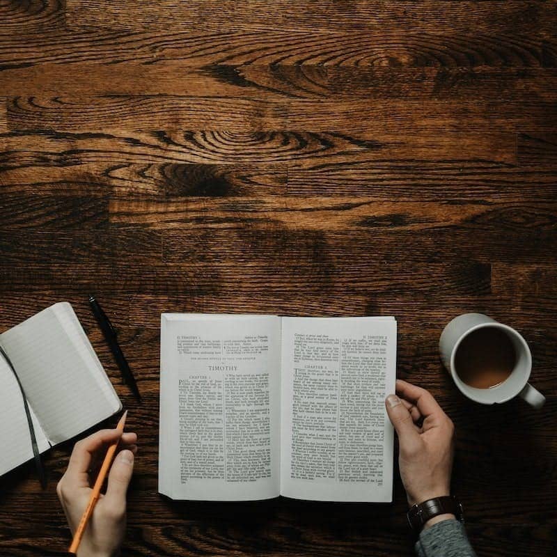 person sitting by the table opening book