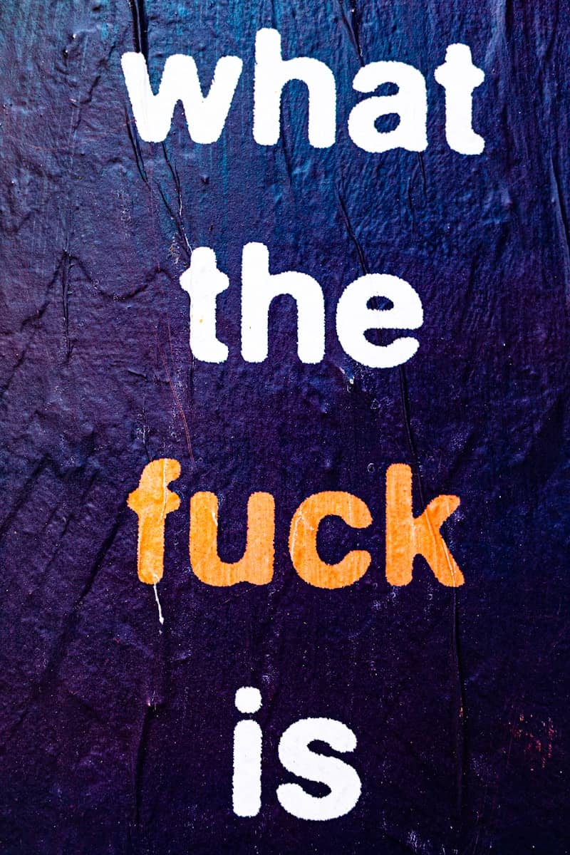 Text 'what the fuck is' on a dark textured background.