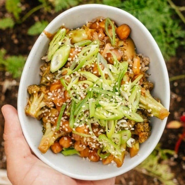 a bowl of roasted cauliflower, sweet potato, topped with green onions.